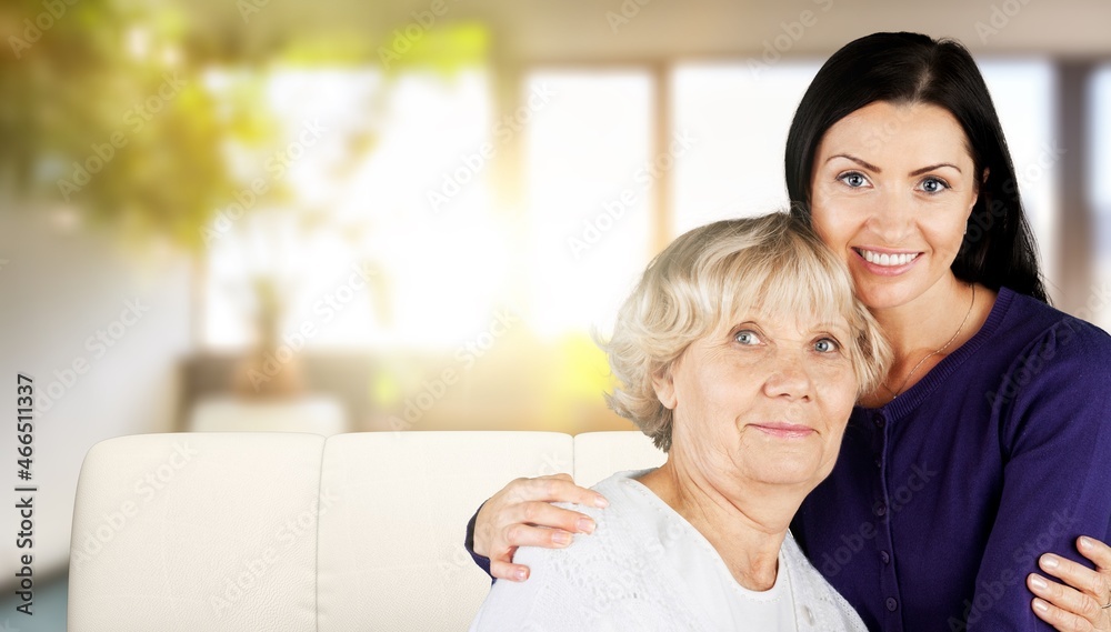 Happy smiling mature mother embracing grownup daughter, having fun, sitting on cozy couch Happy smiling mature mother embracing grownup daughter, having fun, sitting on cozy couch