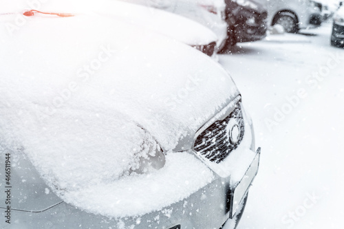 Cars parked in row at outdoor parking in winter. Vehicles covered by snow during heavy snowfall. Snowstorm or blizzard cold season weather forecast. Ice storm automobile park lot storage at morning