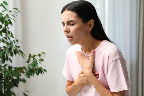 Young woman suffering from breathing problem indoors