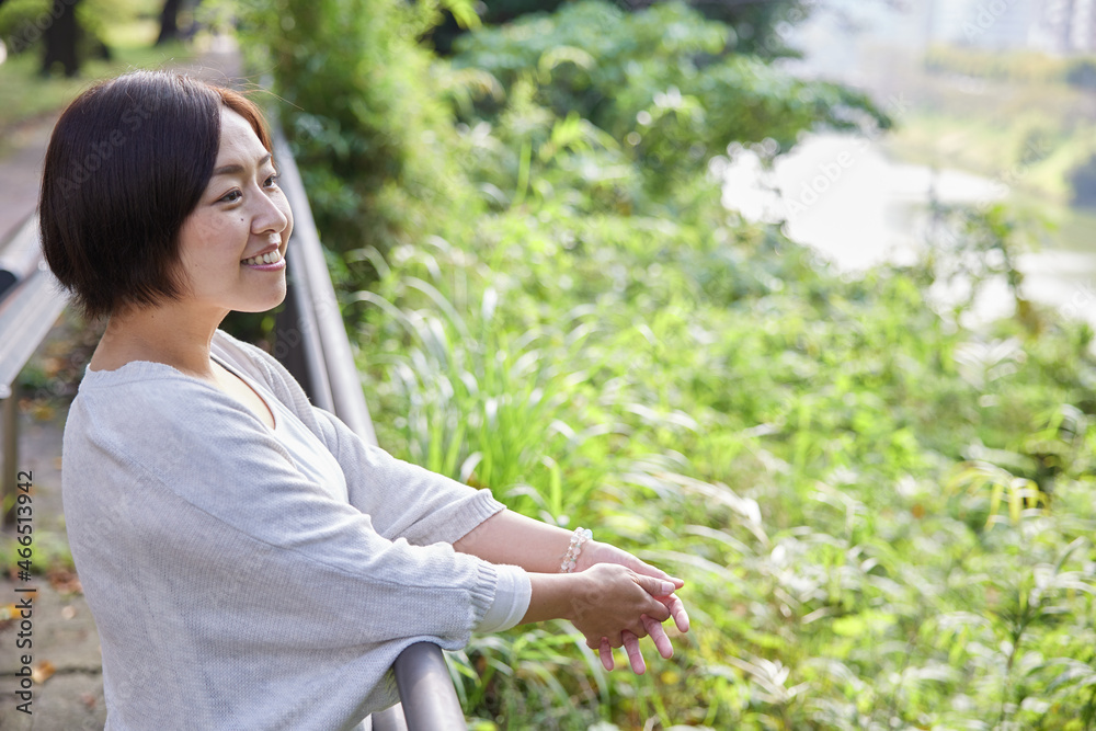 手すりに肘をかけ景色を楽しむ日本人女性 手すりに肘をかけ景色を楽しむ日本人女性