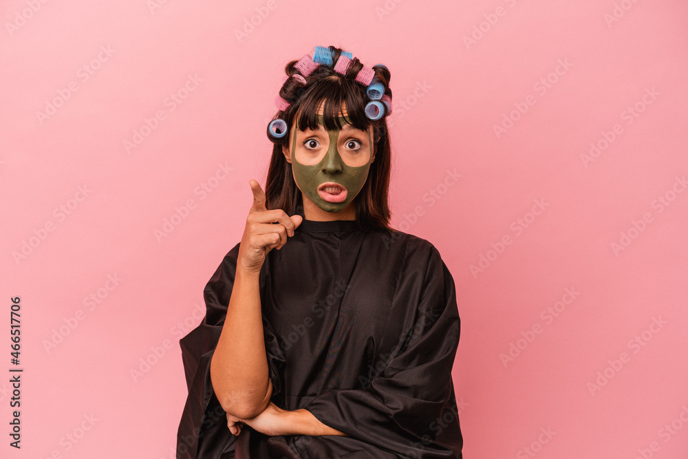 Young mixed race woman waiting in a Beaty salon isolated on pink background having an idea, inspiration concept.