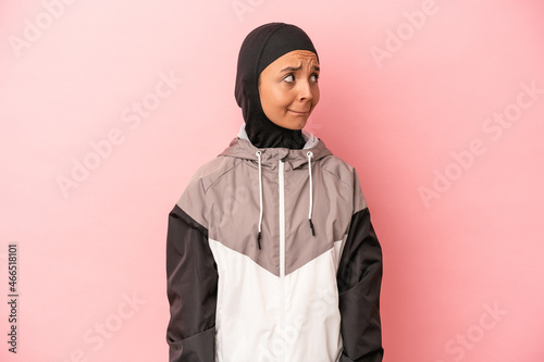 Young Arab woman with sport burqa isolated on pink background confused, feels doubtful and unsure.
