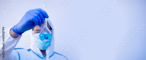 Wide medical banner concept with copy space. Doctor in laboratory wear chemical suit, protection glasses and gloves, holding a flask with vaccine