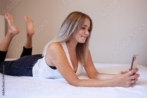 Tableau sur toile Chica tumbada en la cama con el móvil