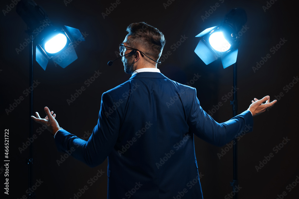 Motivational speaker with headset performing on stage, back view - obrazy, fototapety, plakaty 