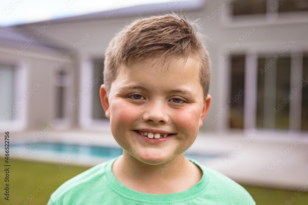 Portrait of smiling caucasian boy with brown hair standing at backyard outside house Portrait of smiling caucasian boy with brown hair standing at backyard outside house