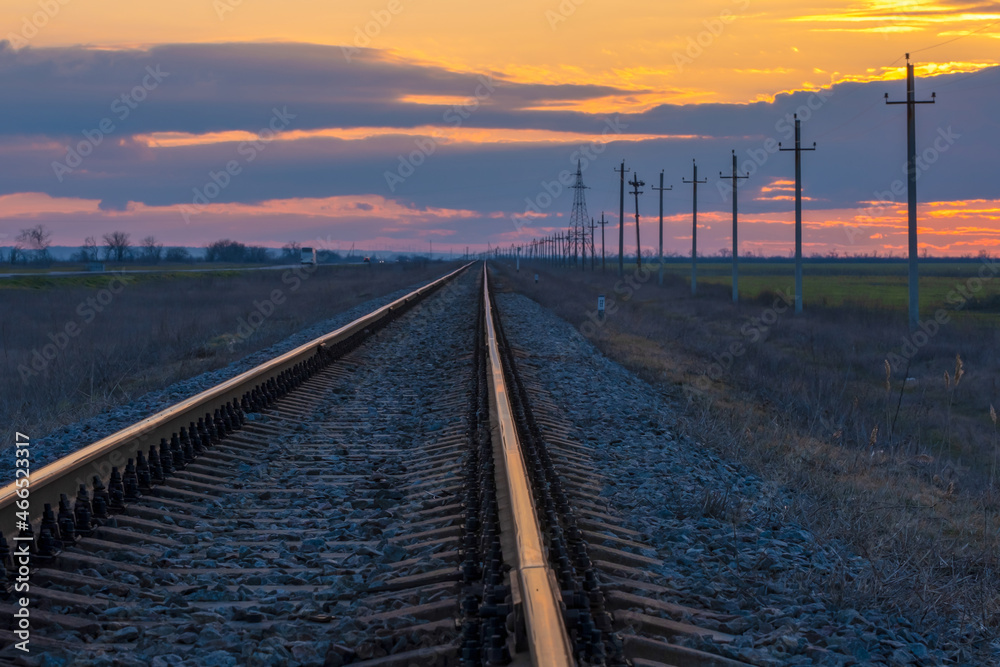 Fototapeta premium Railroad track during sunset. Power line running along the railway.