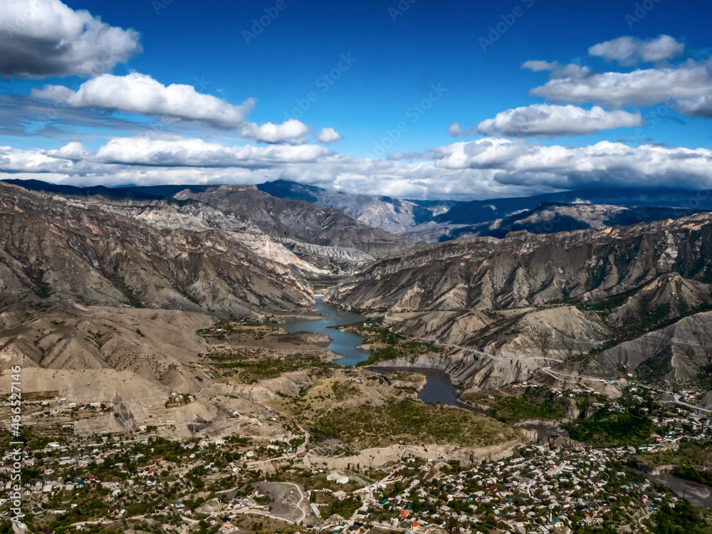 A village near the river between the mountains in Dagestan on a bright autumn day with blue skies and white clouds A village near the river between the mountains in Dagestan on a bright autumn day with blue skies and white clouds