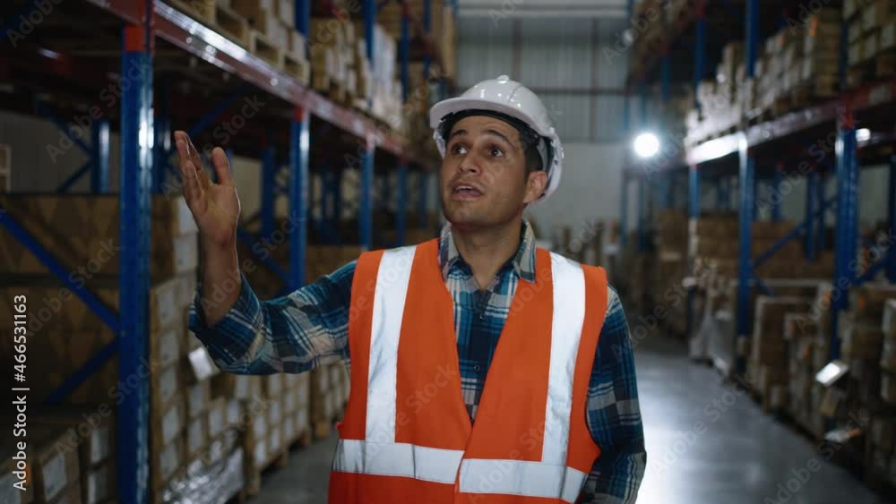 A Caucasian worker is explaining the storage system walking inside distribution warehouse A Caucasian worker is explaining the storage system walking inside distribution warehouse