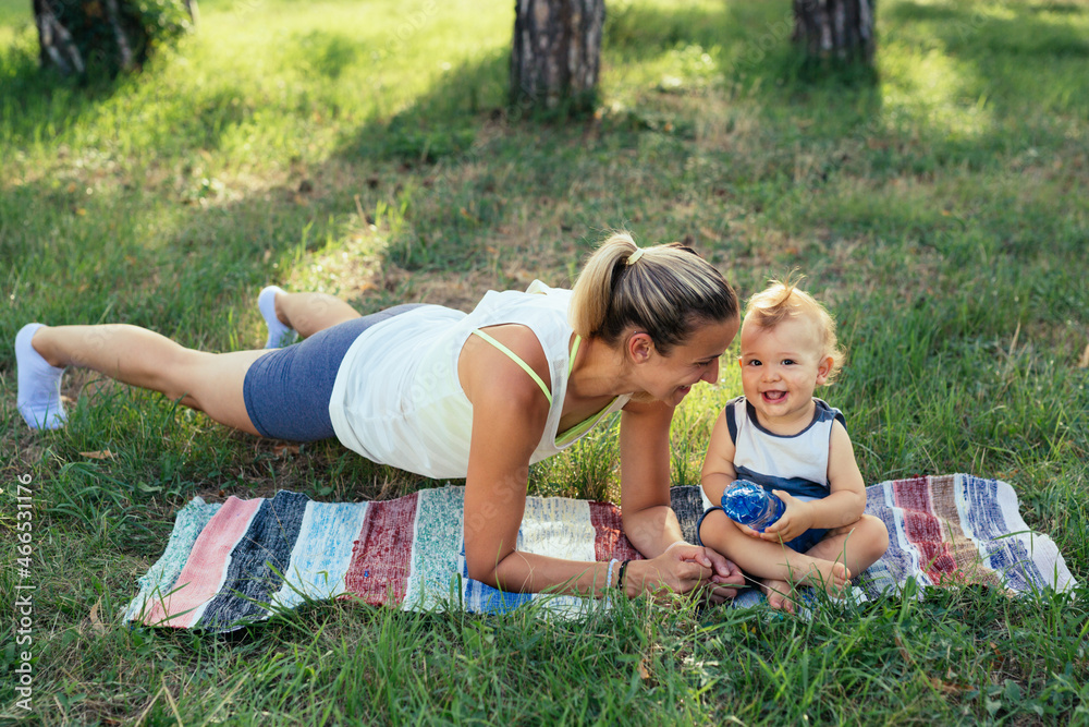 Fototapeta premium mother with her baby boy do physical exercises outdoor in park
