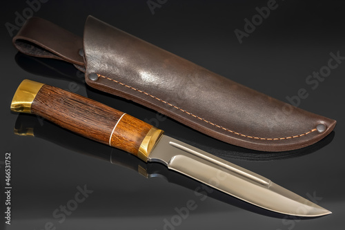 Hunting knife handmade on a black background. Leather sheath handmade.