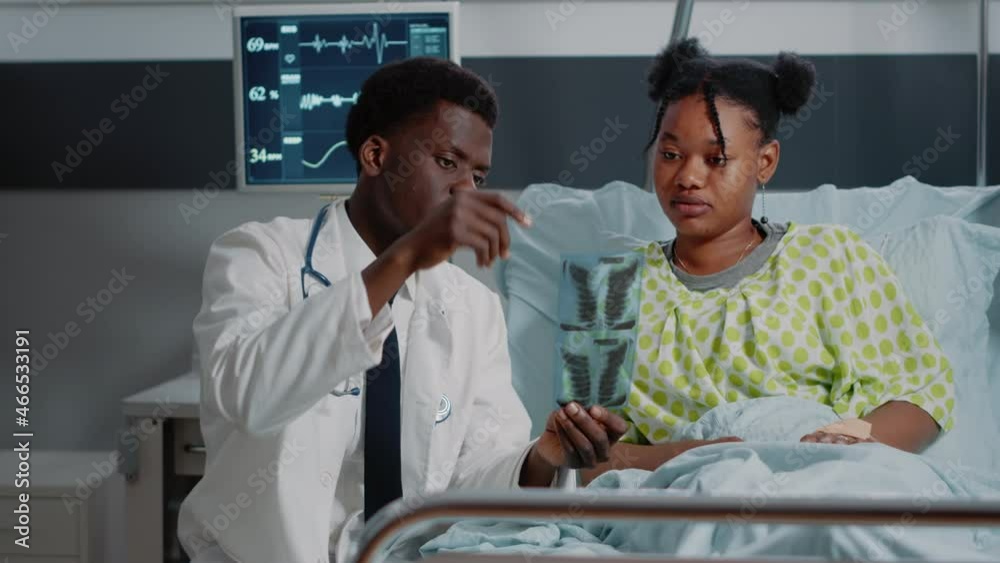 Man working as doctor analyzing x ray scan with sick patient in ...