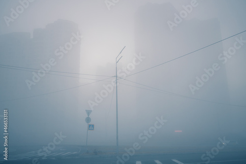 Ghost city. Dreamy morning street view. Foggy silhouettes of modern buildings on a city street. Urban background.