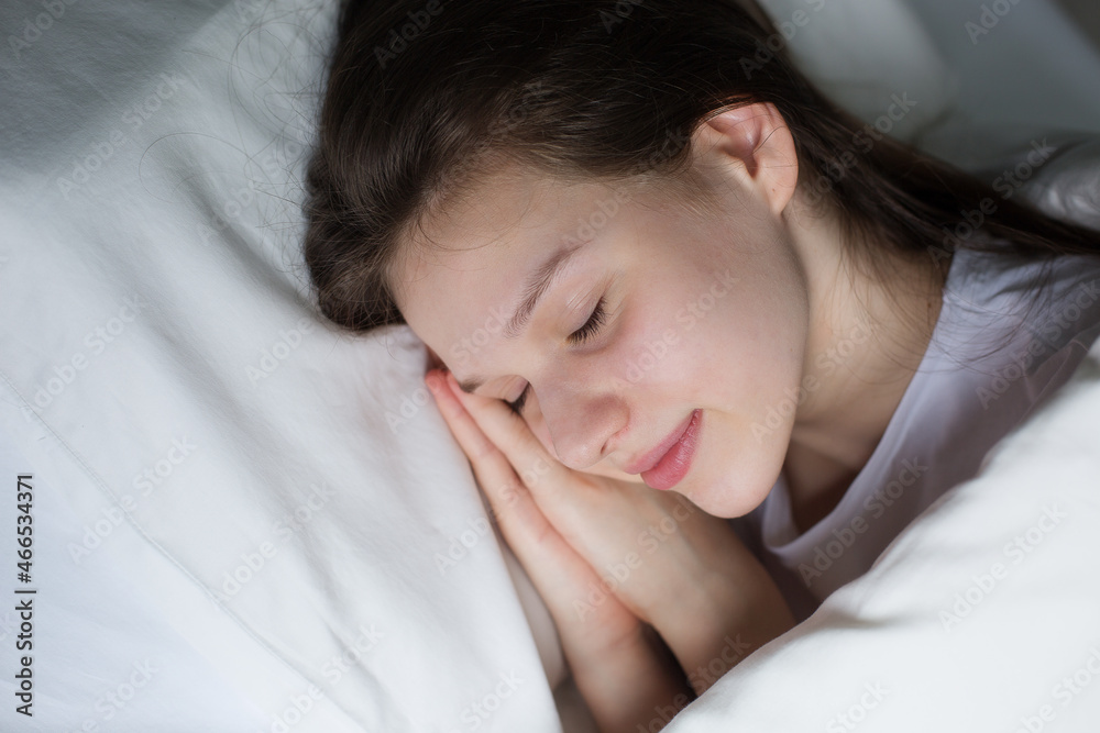Dreaming girl lying on white bed with pillow, enjoying free time at weekend Dreaming girl lying on white bed with pillow, enjoying free time at weekend