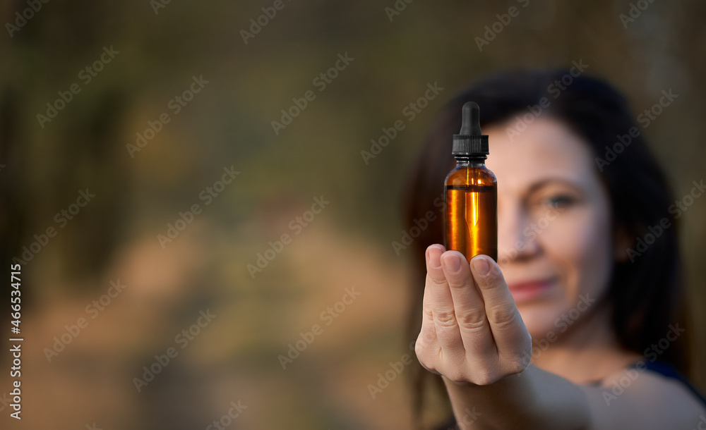 Female holding a dropper bottle of herbal essential oil. Flower therapy BACH, concept. Copy space for text. Female holding a dropper bottle of herbal essential oil. Flower therapy BACH, concept. Copy space for text.