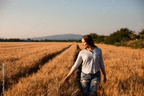 Charming woman enjoying moment, walking in grain field © oksix