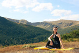 Beautiful young woman practicing yoga in mountains on summer morning