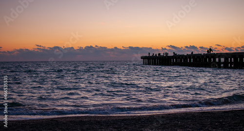 Evening seascape with a pier and fishermen.