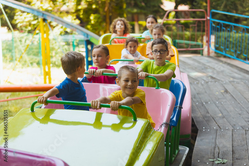 The happy kids on a roller coaster in the amusement park