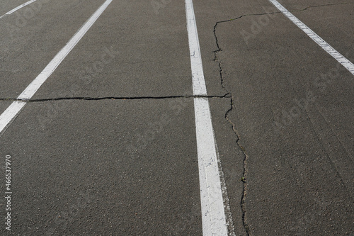 Photo of gray asphalt road with cracks and white markings © Dzmitry