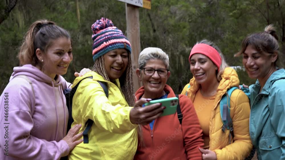 Multiracial women using mobile phone for video call during trekking day into the wood Multiracial women using mobile phone for video call during trekking day into the wood
