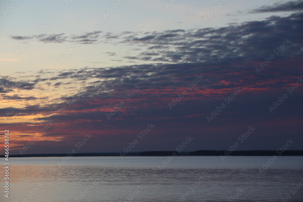 Sunset sky with picturesque purple clouds over the water