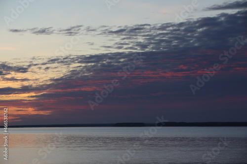 Sunset sky with picturesque purple clouds over the water