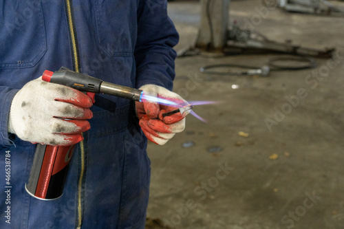 Car master mechanic with gas torch repair heating handmade tool for repairing and restoring car parts in vehicle repair service. Creation of a handmade tool.