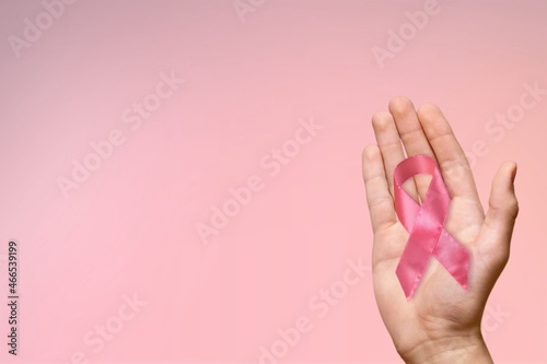 Persons hand holding the pink ribbon in palm symbol of breast cancer awareness