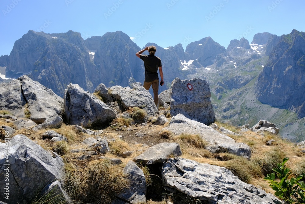 Mountain views during trekking along beautiful tourist loop onMontenegrin side of Prokletije Mountains: Volusnica (1879 m) - Taljanka (2018 m) - Popadija (2057 m). Young man standing on viewpoint.