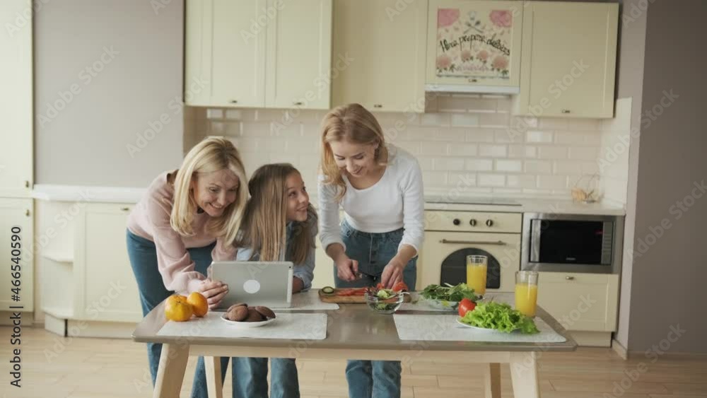 three female generation are cooking vegetables and watching recipes tablet three female generation are cooking vegetables and watching recipes tablet