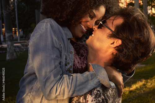  portrait of multiracial couple in love and happy embracing in the park