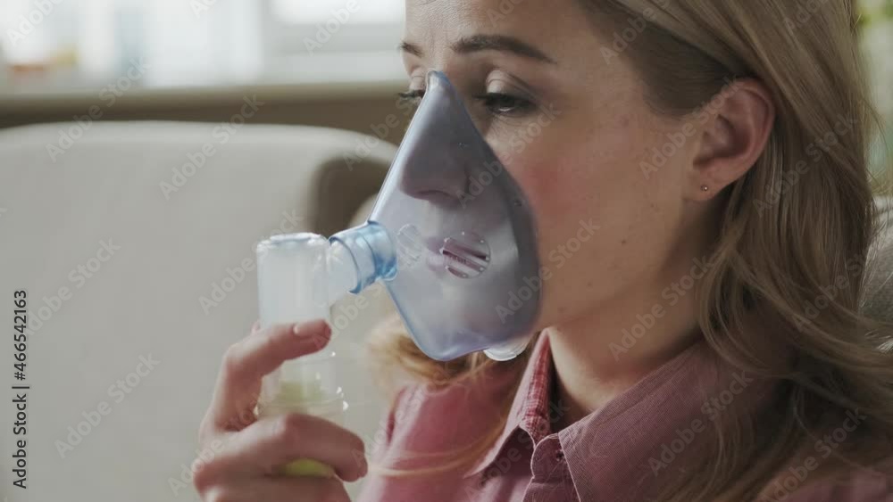 close up sick female using oxygen mask at home, a 30s woman has labored breathing, treatment at