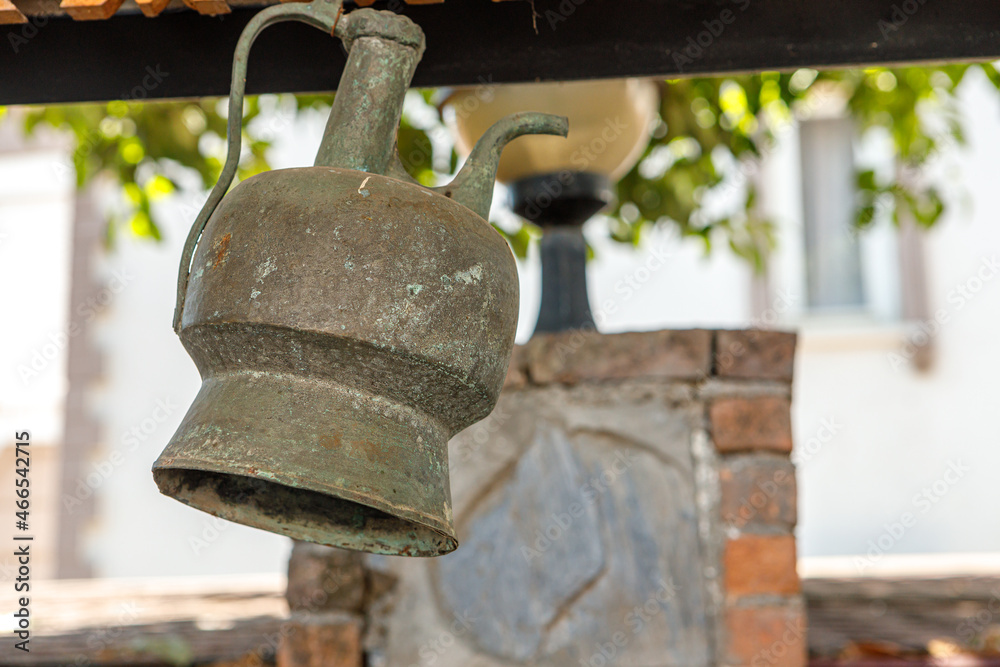 An antique copper jug is hanging outdoors. Antiques. An antique copper jug is hanging outdoors. Antiques.
