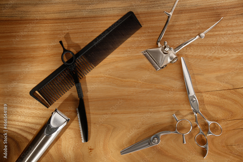 Professional hairdressing tools, scissors, comb, trimmer on wooden table. Hairdressing devices. Close up. Selective focus on scissors Professional hairdressing tools, scissors, comb, trimmer on wooden table. Hairdressing devices. Close up. Selective focus on scissors