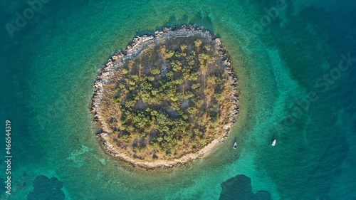 Aerial drone top down photo of small tropical exotic island covered in limestone with emerald sea