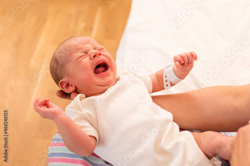 Mom holds her screaming baby in her arms photo