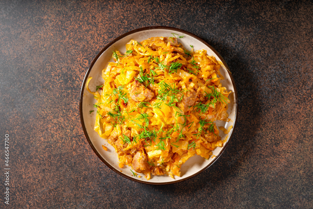 Braised cabbage. Stewed cabbage or bigos with turkey meat in a ceramic plate on a dark background. Traditional Polish dish Braised cabbage. Stewed cabbage or bigos with turkey meat in a ceramic plate on a dark background. Traditional Polish dish