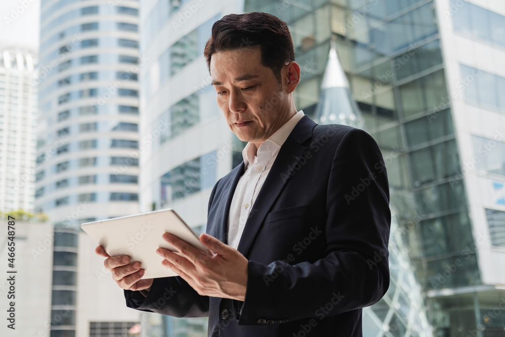 Low Angle View of Handsome Asian Businessman Using Digital Tablet Outside Office Low Angle View of Handsome Asian Businessman Using Digital Tablet Outside Office