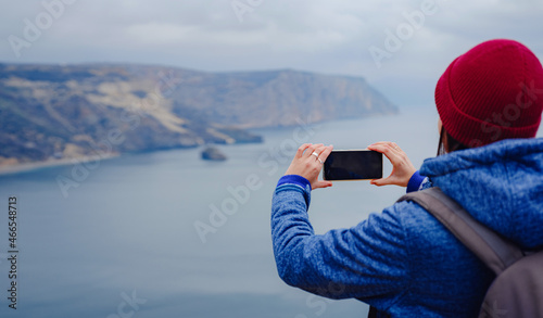 A woman take a photo of the sea on smartphone, female travels along the coast in the cold season. Outdoor. POV. Close up