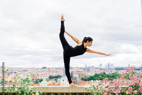Female does yoga in the background of the city of Prague