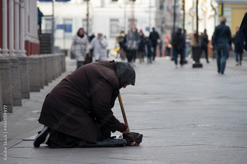 The concept of poverty - old woman in bad clothes begs for money in crowd place The concept of poverty - old woman in bad clothes begs for money in crowd place