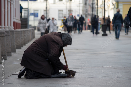 The concept of poverty - old woman in bad clothes begs for money in crowd place