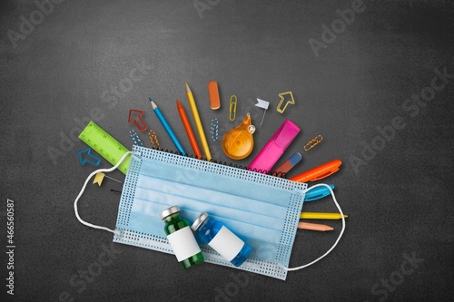 School stationery supplies, medical masks on the desk. back to school after covid-19 photo