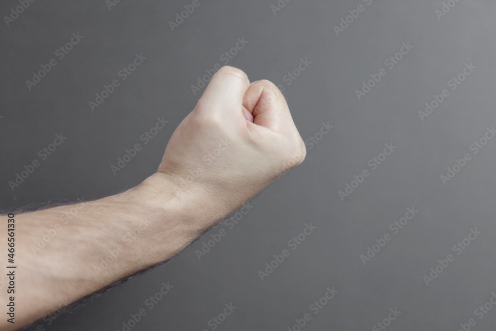Male hand clenching a fist on a light gray background, close-up. Copy space. Male hand clenching a fist on a light gray background, close-up. Copy space.