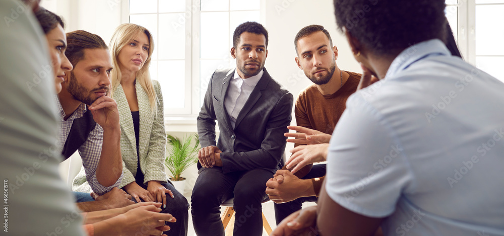 Young diverse business team talking during work meeting. Banner with group of serious multiracial multiethnic people sitting in circle, discussing important things, listening to colleague's suggestion - obrazy, fototapety, plakaty 