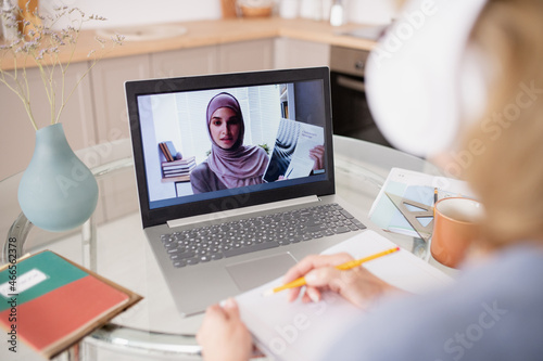 Young teacher on laptop screen showing document to online student while presenting and explaining information