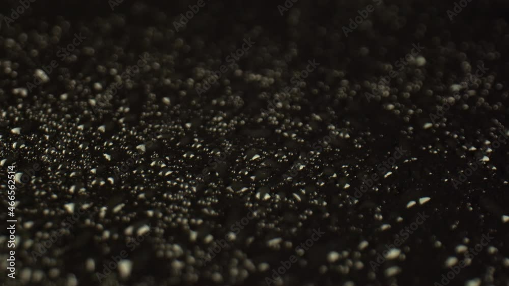 Transparent drops of water cover the black surface of the table, a close-up. A scattering of beautiful raindrops on a dark background. High quality. 4k footage. Transparent drops of water cover the black surface of the table, a close-up. A scattering of beautiful raindrops on a dark background. High quality. 4k footage.
