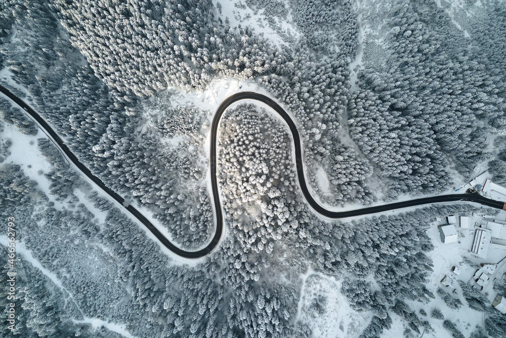 Aerial view of winter landscape with snow covered mountain woods and winding forest slippery road