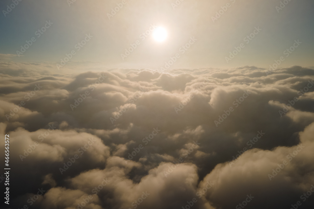 Aerial view from airplane window at high altitude of dense puffy cumulus clouds forming before rainstorm in evening